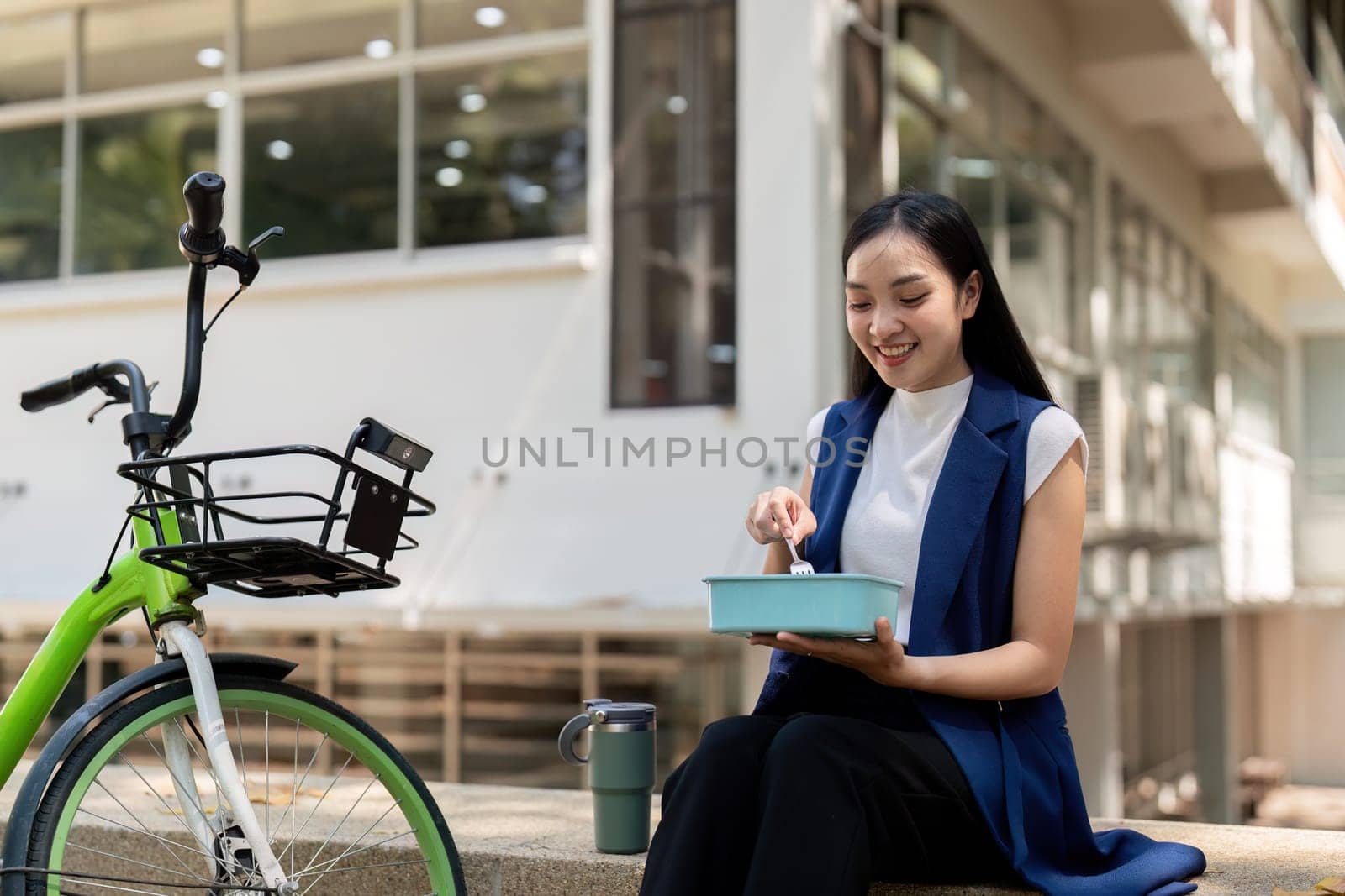 Businesswoman enjoying a lunch break outdoors with her bicycle parked nearby. Concept of work life balance, healthy eating, and sustainable commuting.