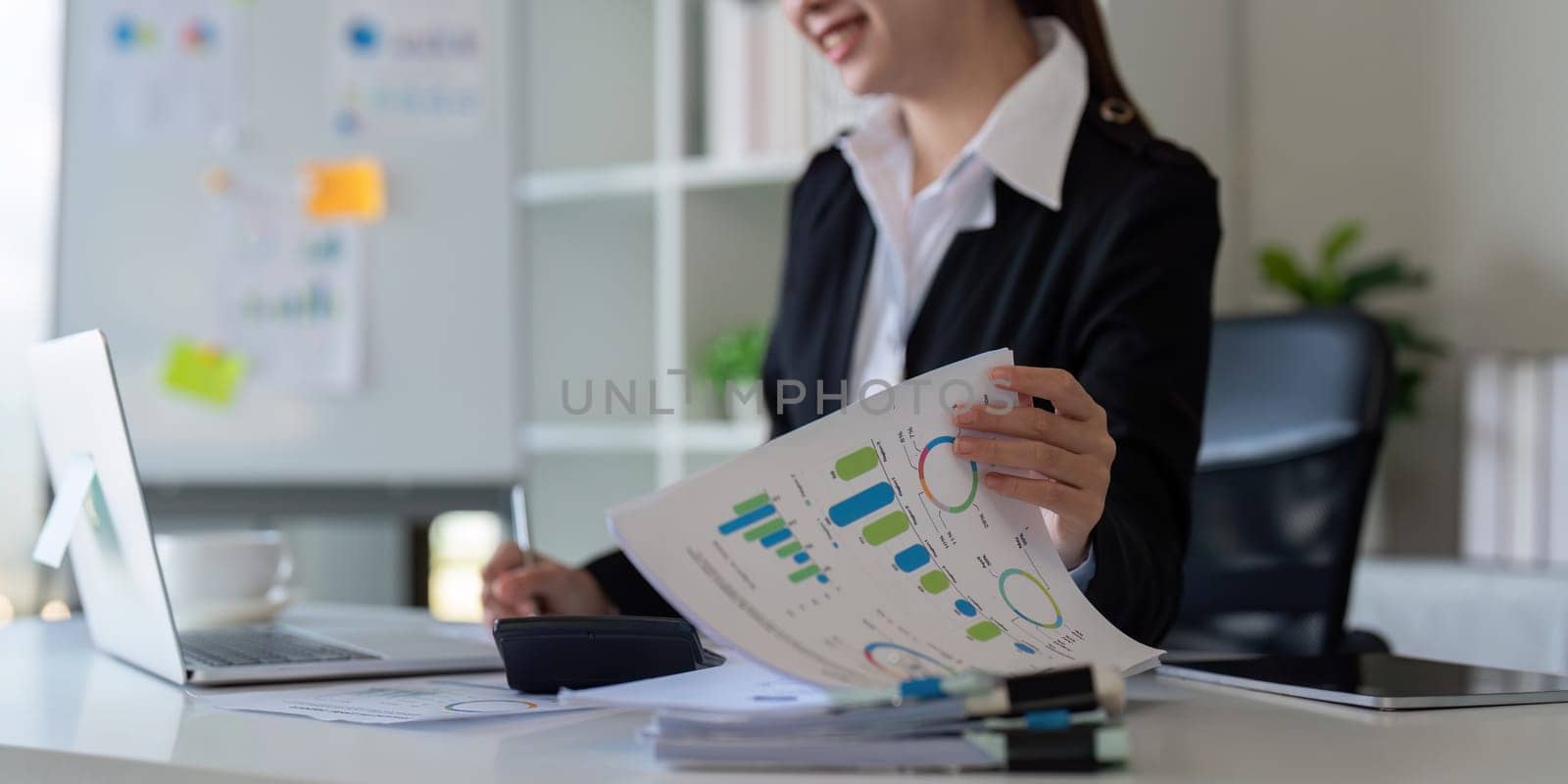 Businesswoman analyzing charts in office. Concept of finance, technology, and productivity.