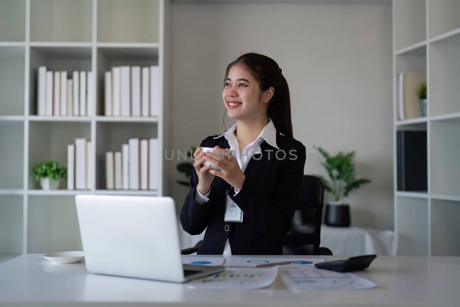 Businesswoman drinking coffee in office. Concept of relaxation, technology, and productivity.
