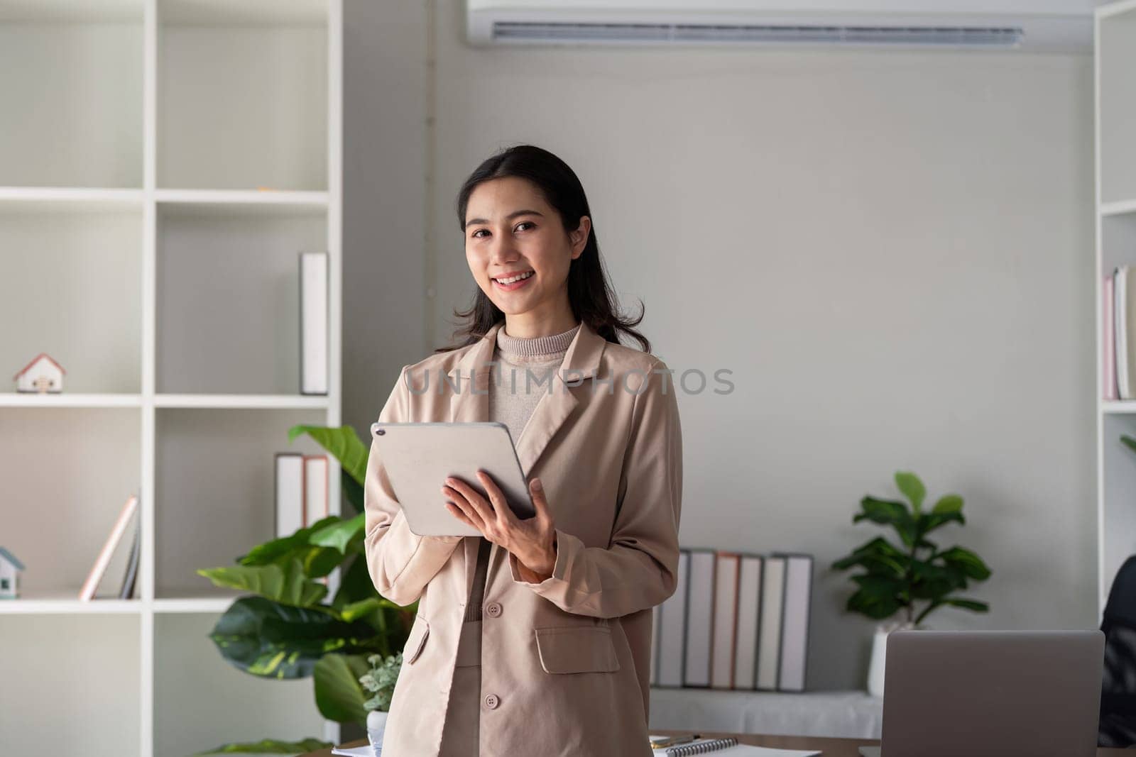 Businesswoman holding tablet and smiling in office. Concept of modern technology and professional work environment.