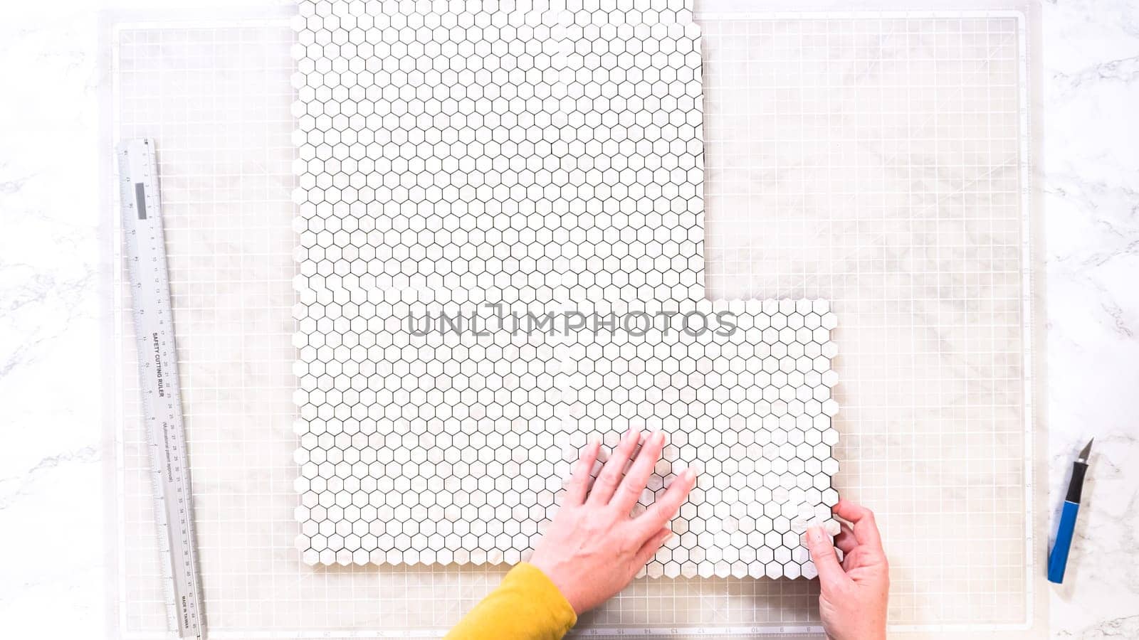 Flat lay. In the process of mounting peel and stick mosaic tiles onto a foam board, perfect for enhancing a food photography studio's aesthetic.