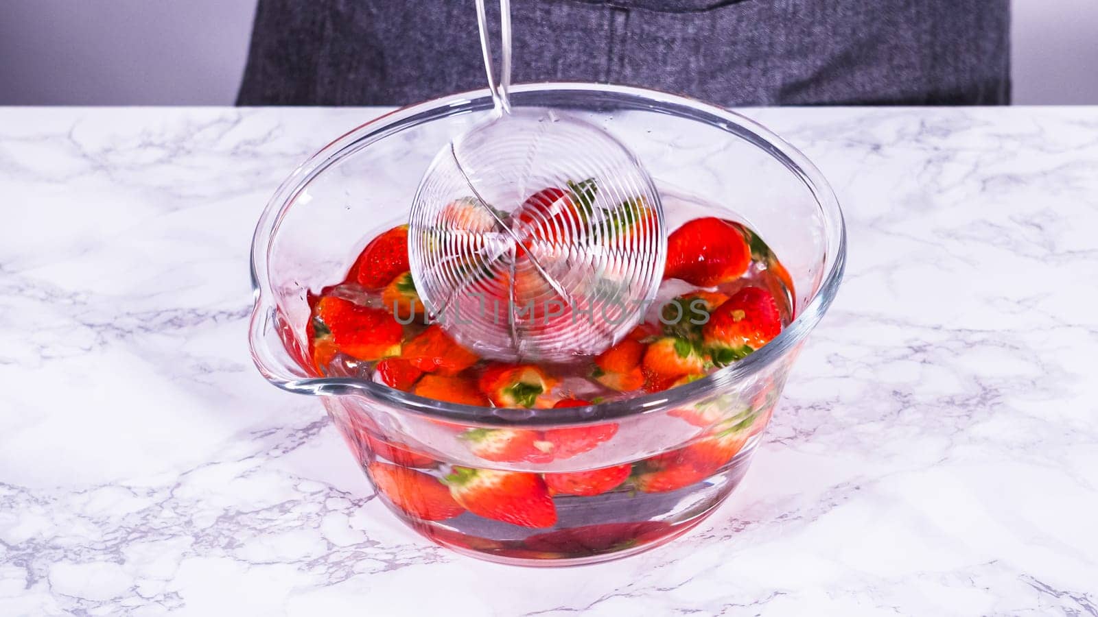 Preparing Strawberries in a Glass Mixing Bowl with Water by arinahabich