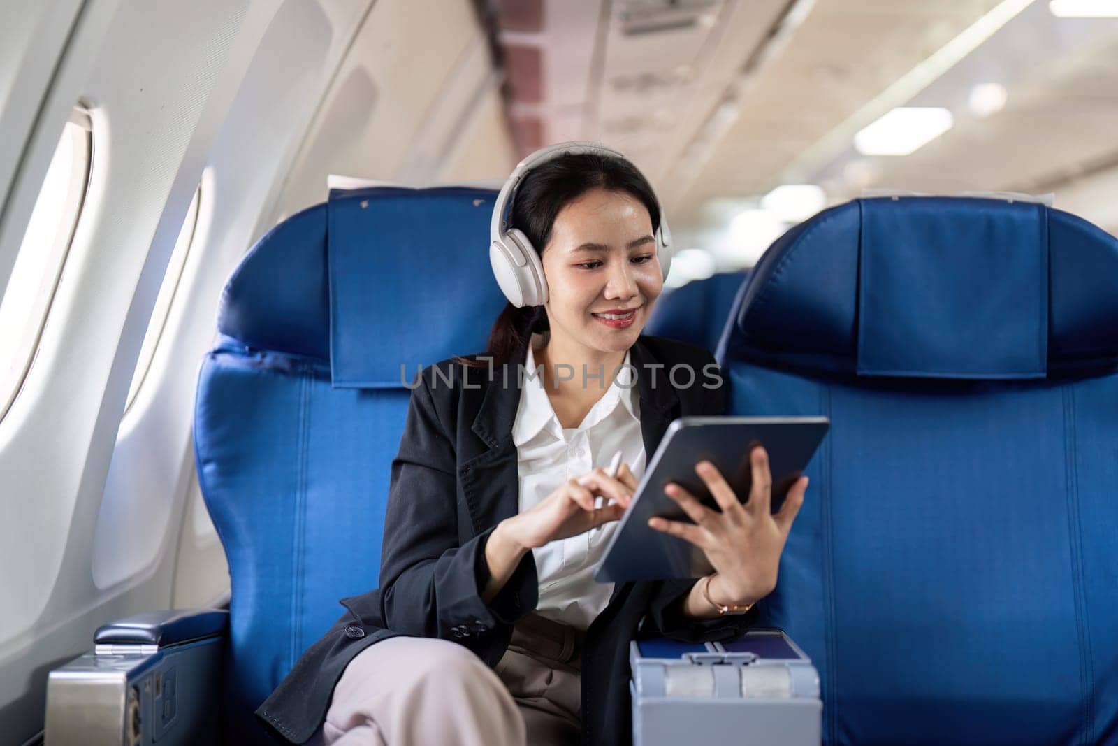 Businesswoman working on tablet during flight. Concept of business travel and technology.