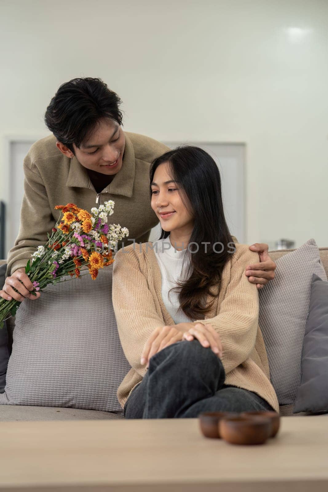 Young couple sharing flowers at home. Concept of love, affection, and togetherness.