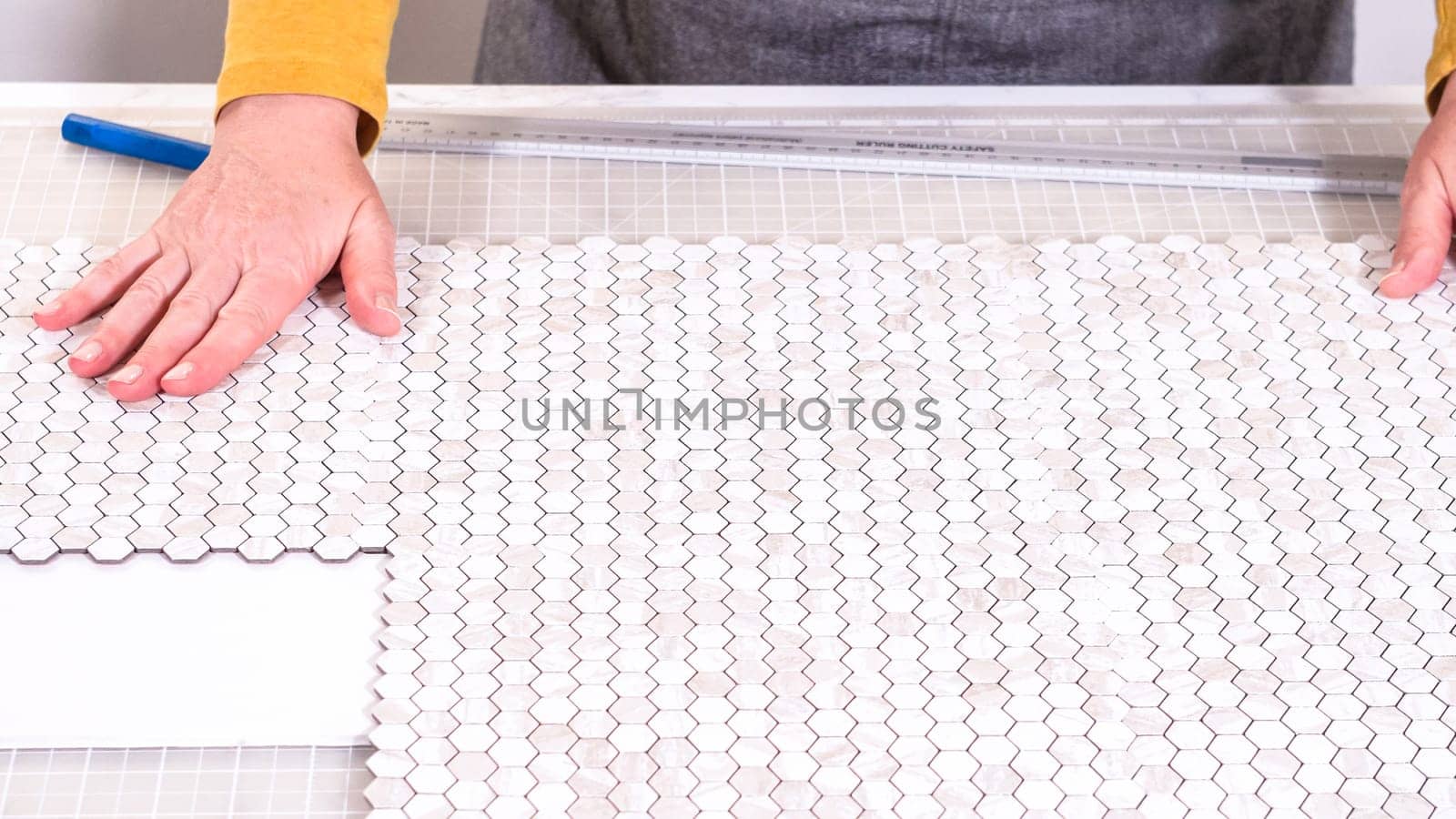 In the process of mounting peel and stick mosaic tiles onto a foam board, perfect for enhancing a food photography studio's aesthetic.