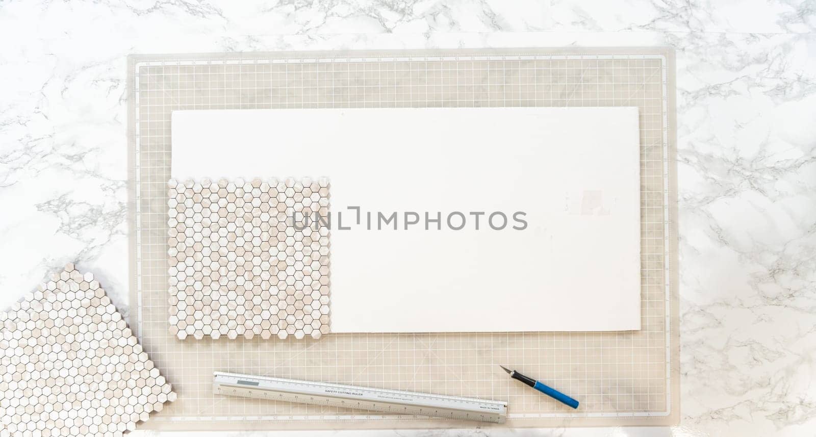 In the process of mounting peel and stick mosaic tiles onto a foam board, perfect for enhancing a food photography studio's aesthetic.