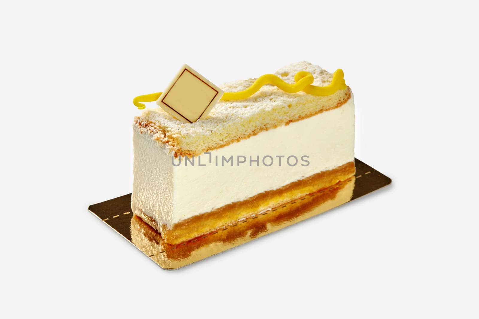 Light dessert of creamy mousse between layers of soft vanilla sponge cake decorated with branded chocolate plaque and yellow swirl, presented on golden cardboard base