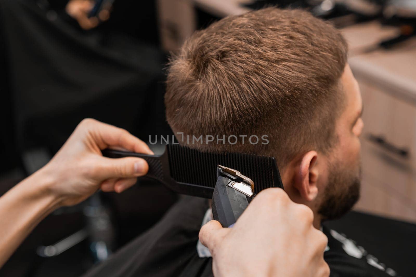 Barber skillfully shaves the clients hair on the back of the head with an electrical trimmer