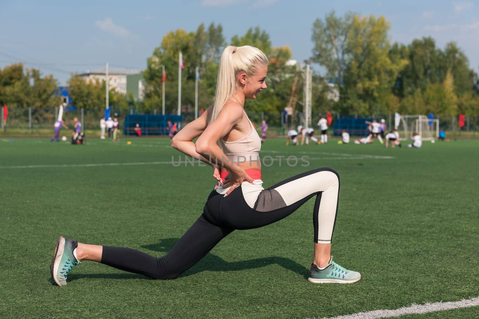 Young sporty woman in sportswear stretching on stadium