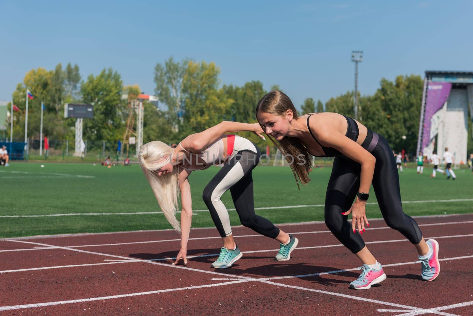 Two athlete young woman runnner on the start at the stadium outdoors