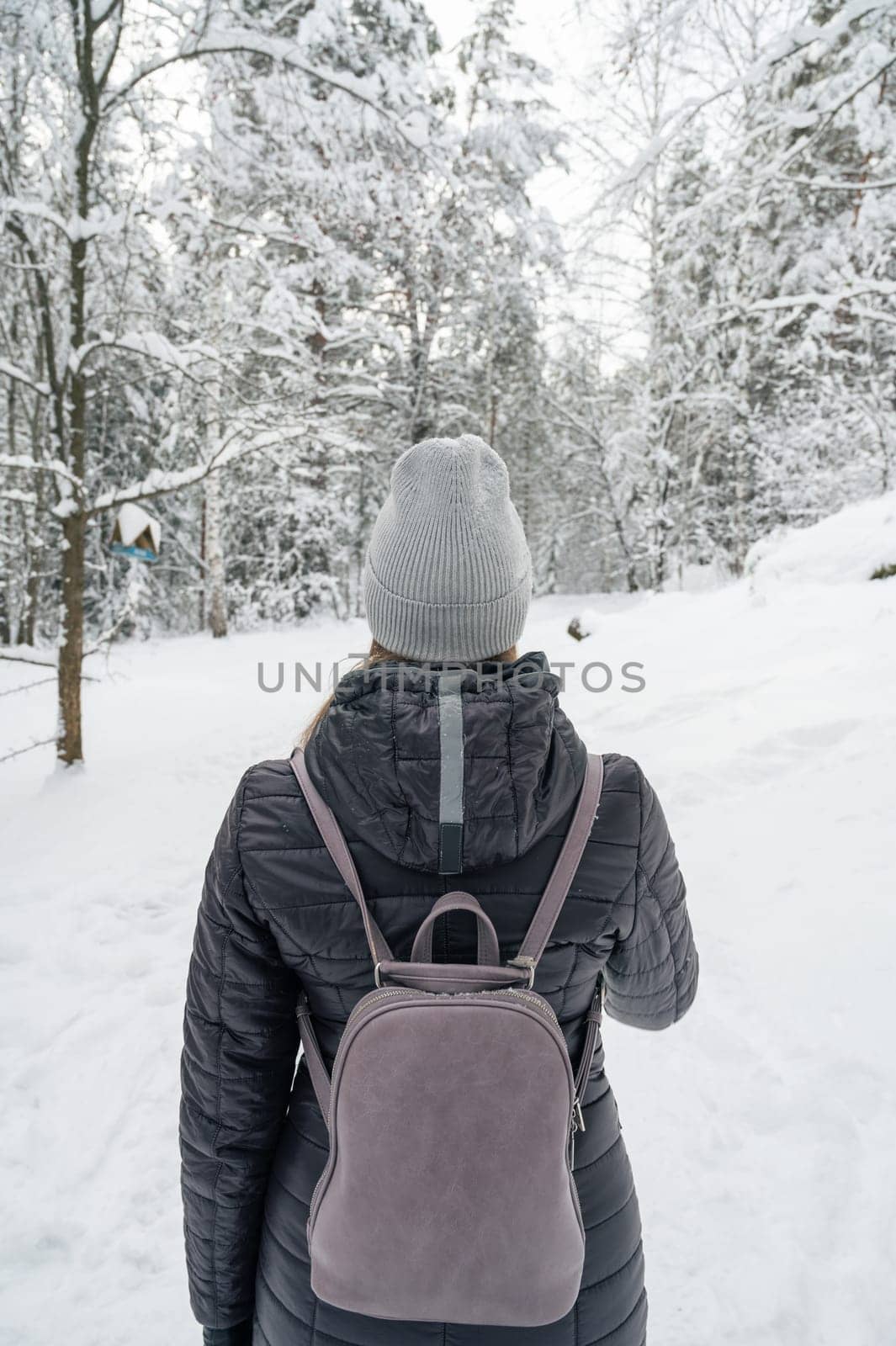 Woman in winter jacket walking in snowy winter forest, snowy winter day