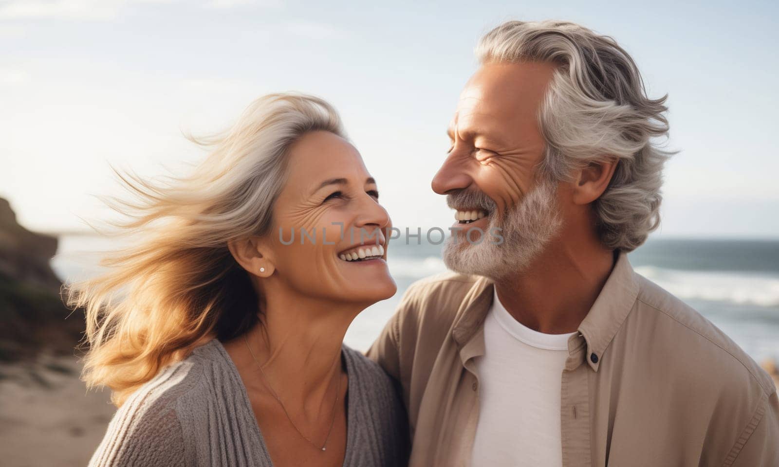 Summer portrait of happy smiling mature gray-haired couple standing together on sunny coast, woman and man enjoying beach vacation at sea