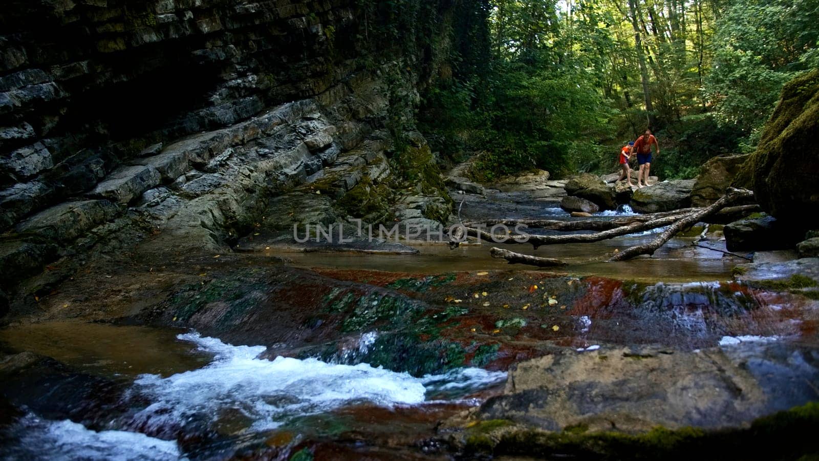 Mother and child in fast flowing mountain river on a summer day. Creative. Hiking in summer jungles