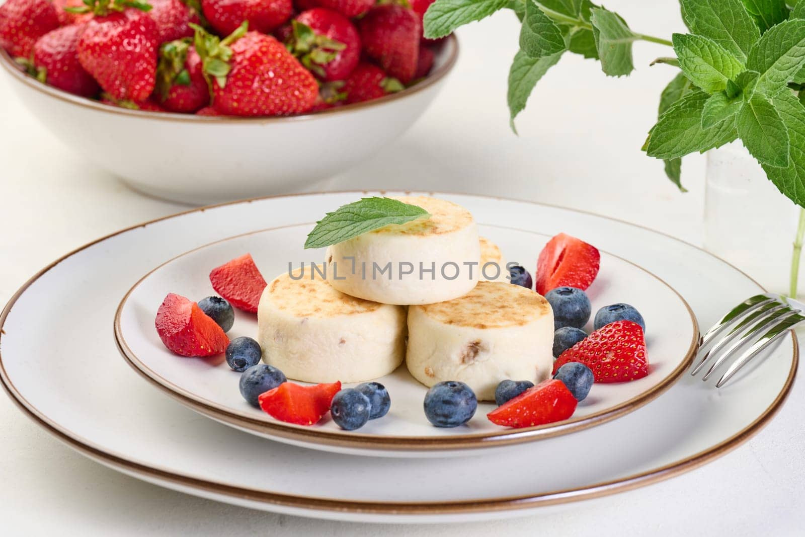 Stack of four cheesecakes on a plate with berries, blueberries, strawberries and cherries. Background white