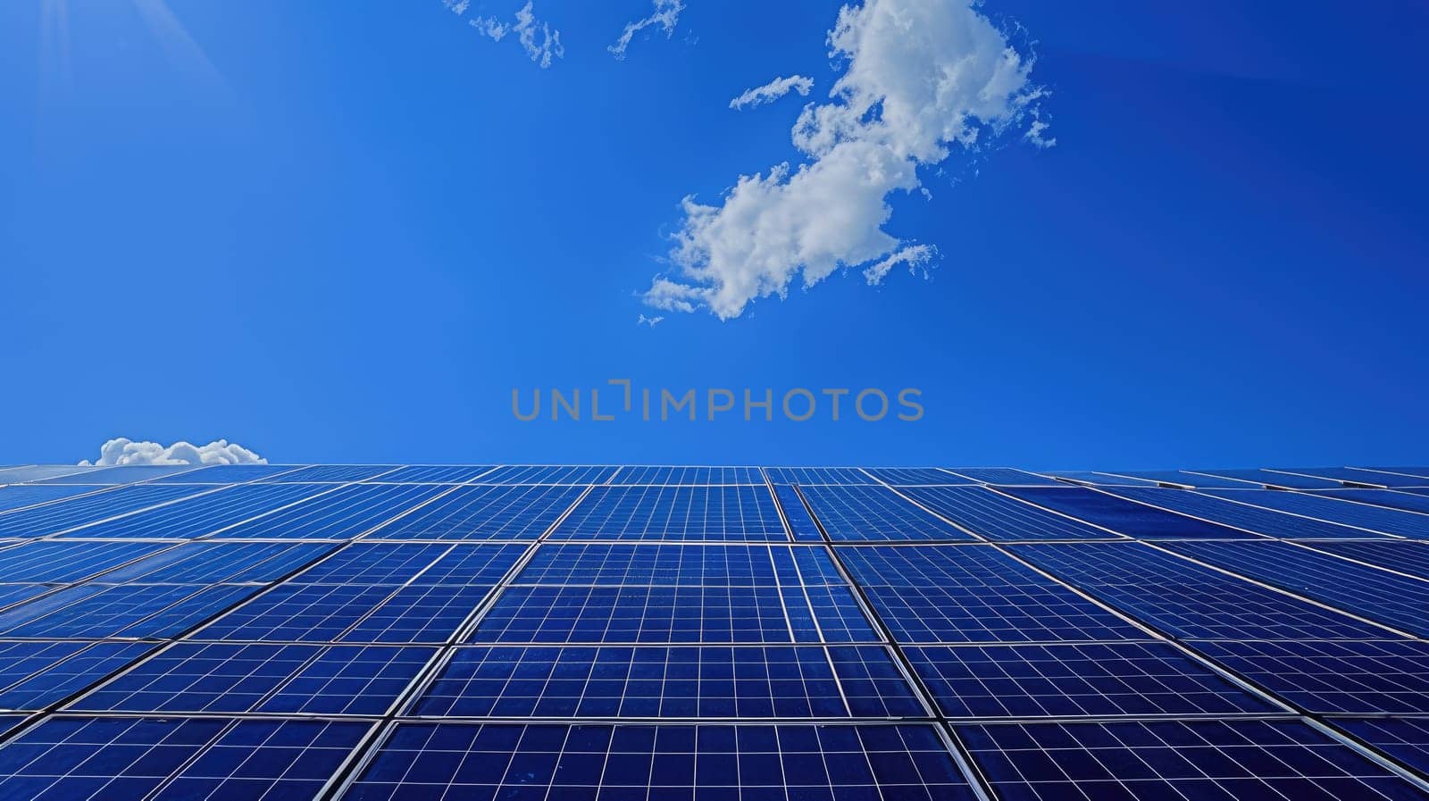 A solar panels and clear blue sky with a few clouds and the sun shining brightly..