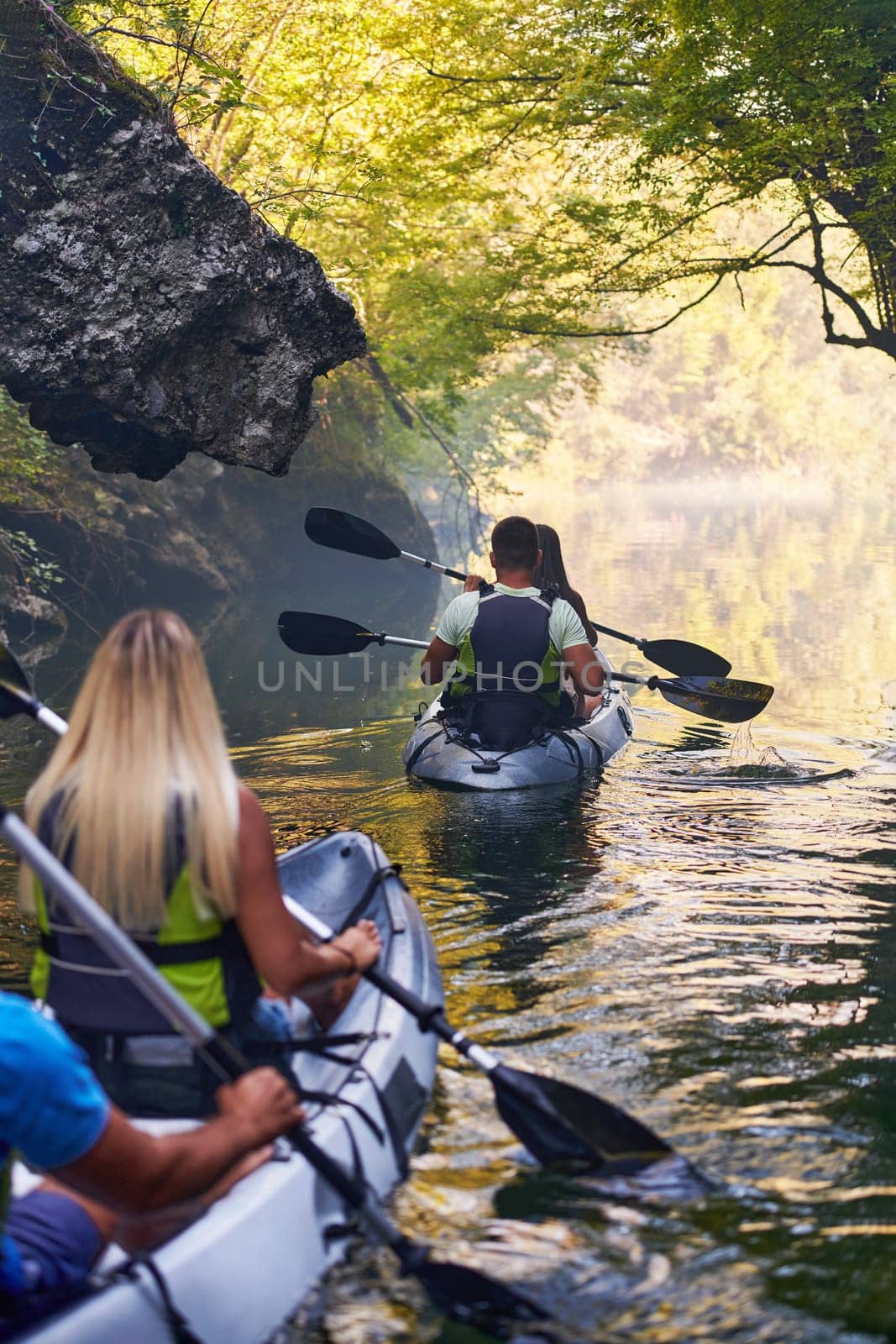 A group of friends enjoying having fun and kayaking while exploring the calm river, surrounding forest and large natural river canyons.