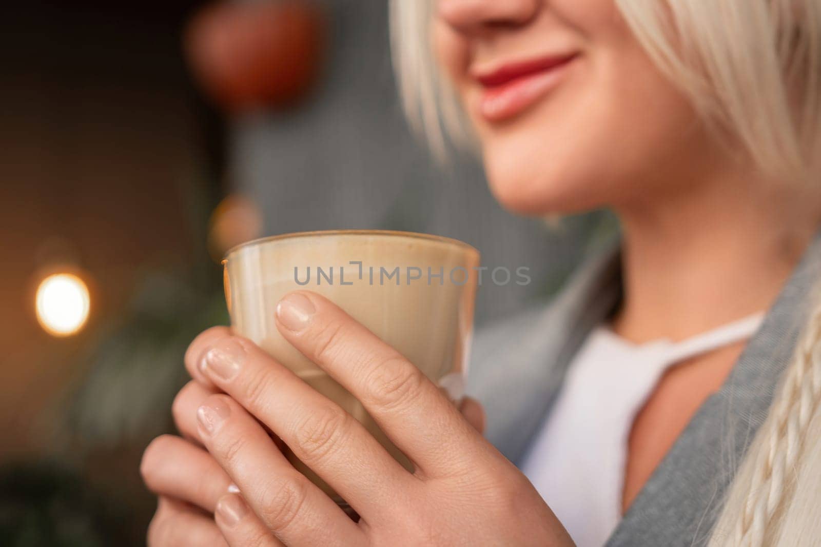 A woman is holding a cup of coffee and smiling. Concept of warmth and relaxation, as the woman enjoys her beverage