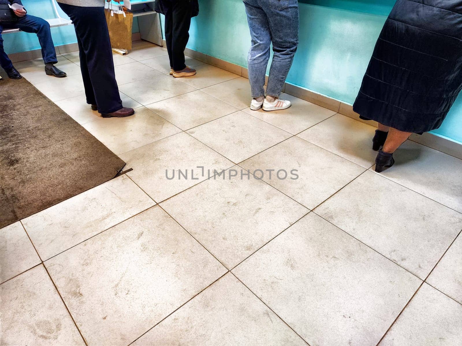 Counter During Daytime. Individuals line up at a counter, possibly at a bank or hospital, awaiting service