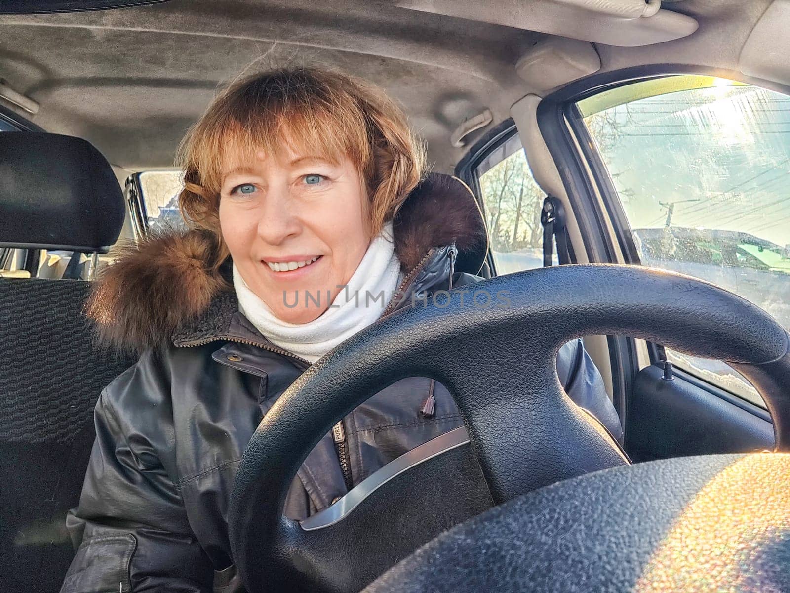 A woman in a car taking a selfie while enjoying a drive. Female driver posing inside car