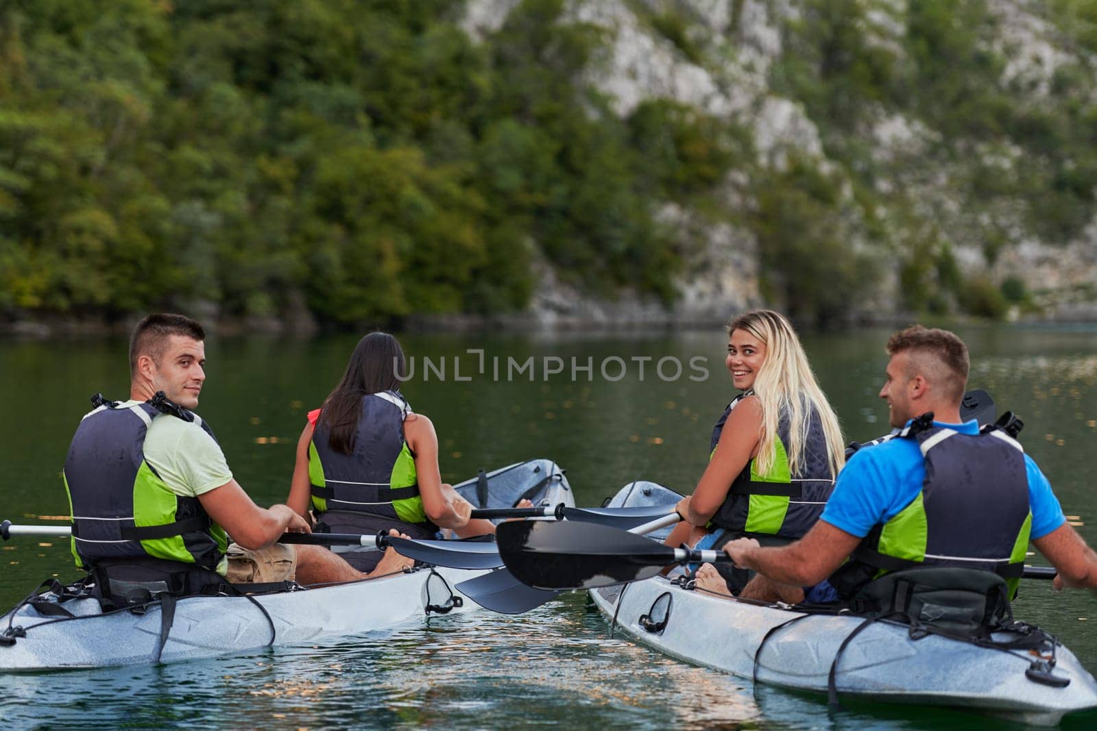 A group of friends enjoying having fun and kayaking while exploring the calm river, surrounding forest and large natural river canyons.