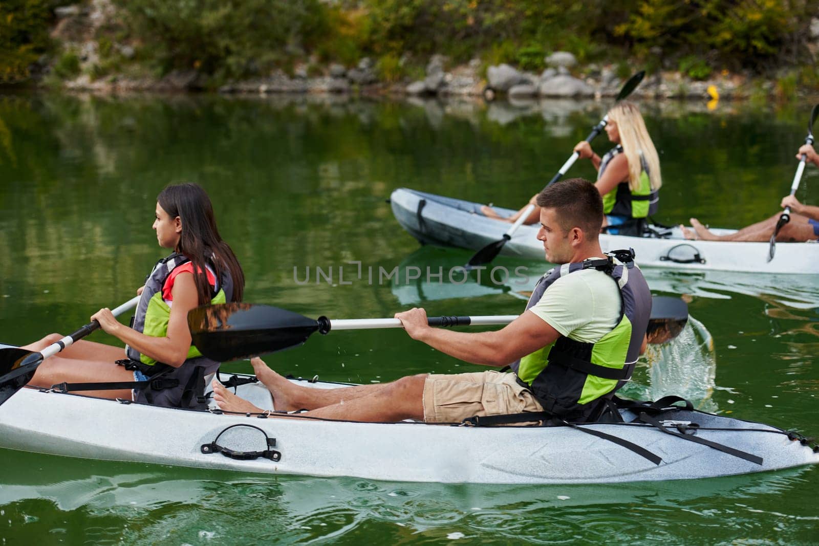 A group of friends enjoying having fun and kayaking while exploring the calm river, surrounding forest and large natural river canyons.