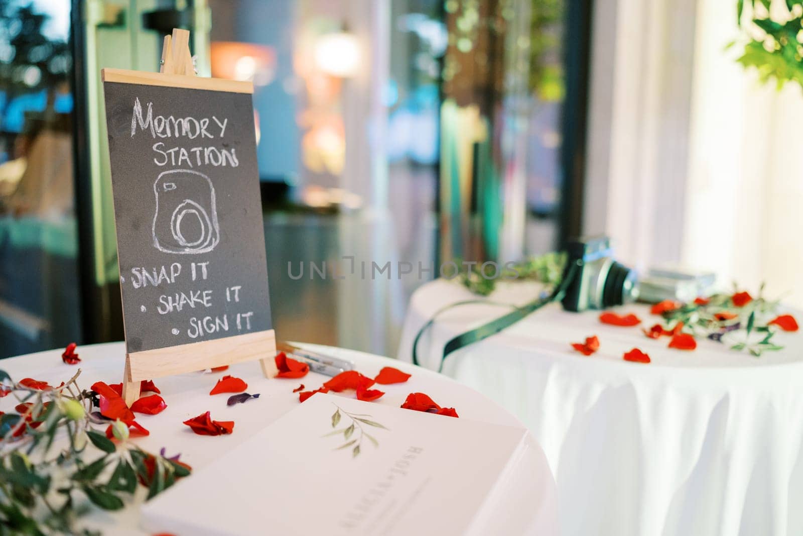 Sign on the table among red petals. Caption: Memory station. High quality photo