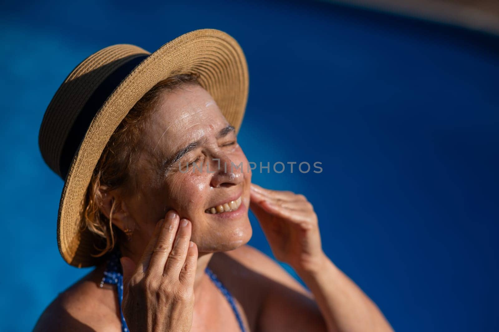 Portrait of an older woman applying sunscreen to her face while on vacation