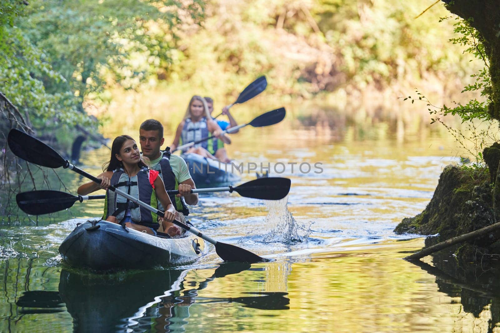 A group of friends enjoying having fun and kayaking while exploring the calm river, surrounding forest and large natural river canyons.