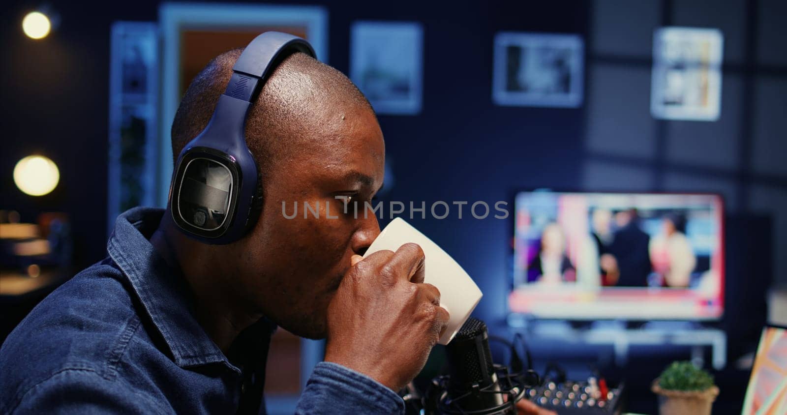 African american show host recording podcast with guest, using analog mixer and professional mic in studio. Close up shot of man setting up audio devices for live broadcast for flawless sound quality
