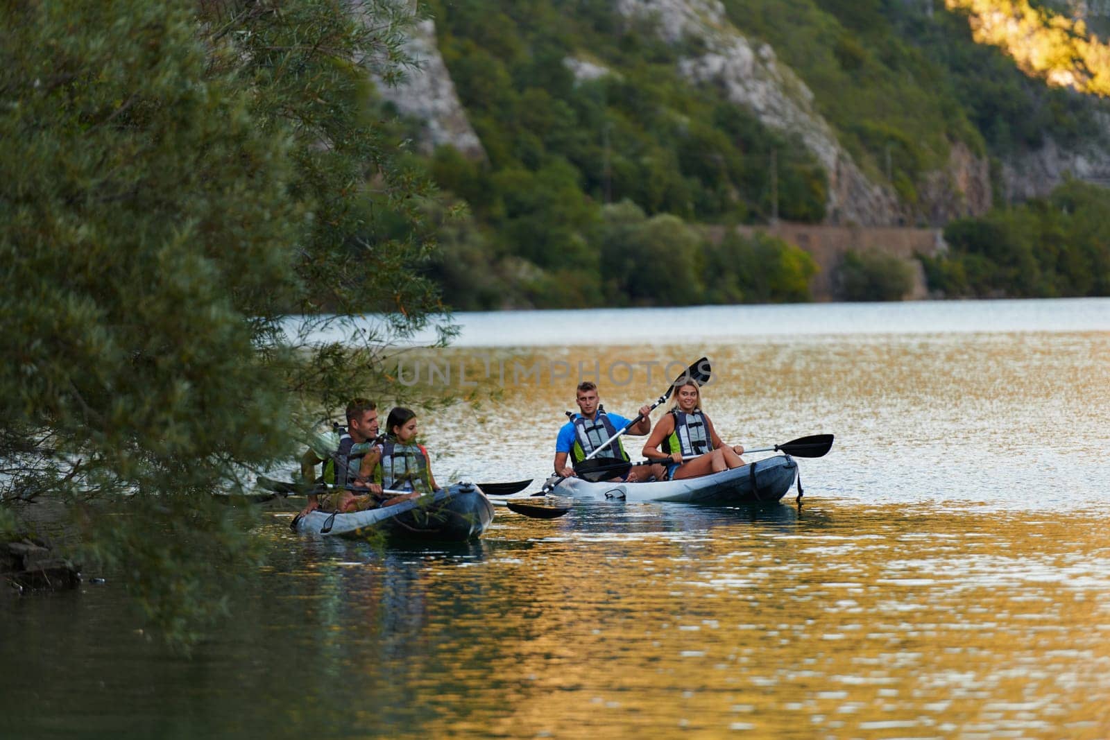 A group of friends enjoying having fun and kayaking while exploring the calm river, surrounding forest and large natural river canyons.