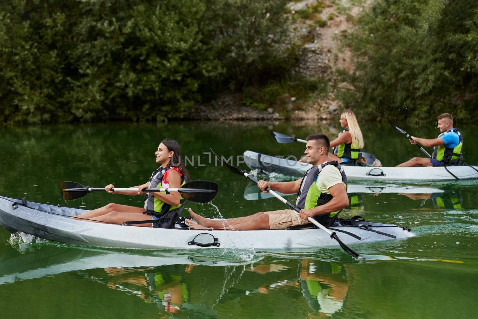 A group of friends enjoying having fun and kayaking while exploring the calm river, surrounding forest and large natural river canyons.