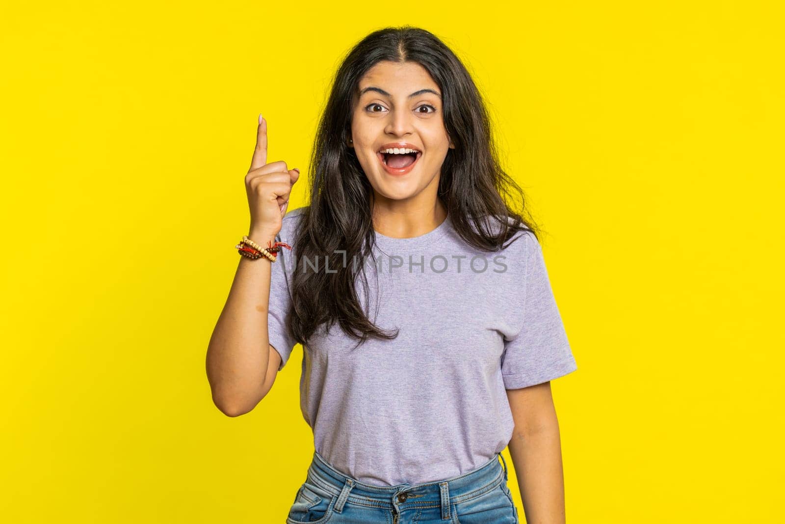 Eureka. Inspired Indian woman pointing finger up with open mouth, having good idea, plan, startup, showing inspiration motivation gesture, problem solution. Arabian girl isolated on yellow background