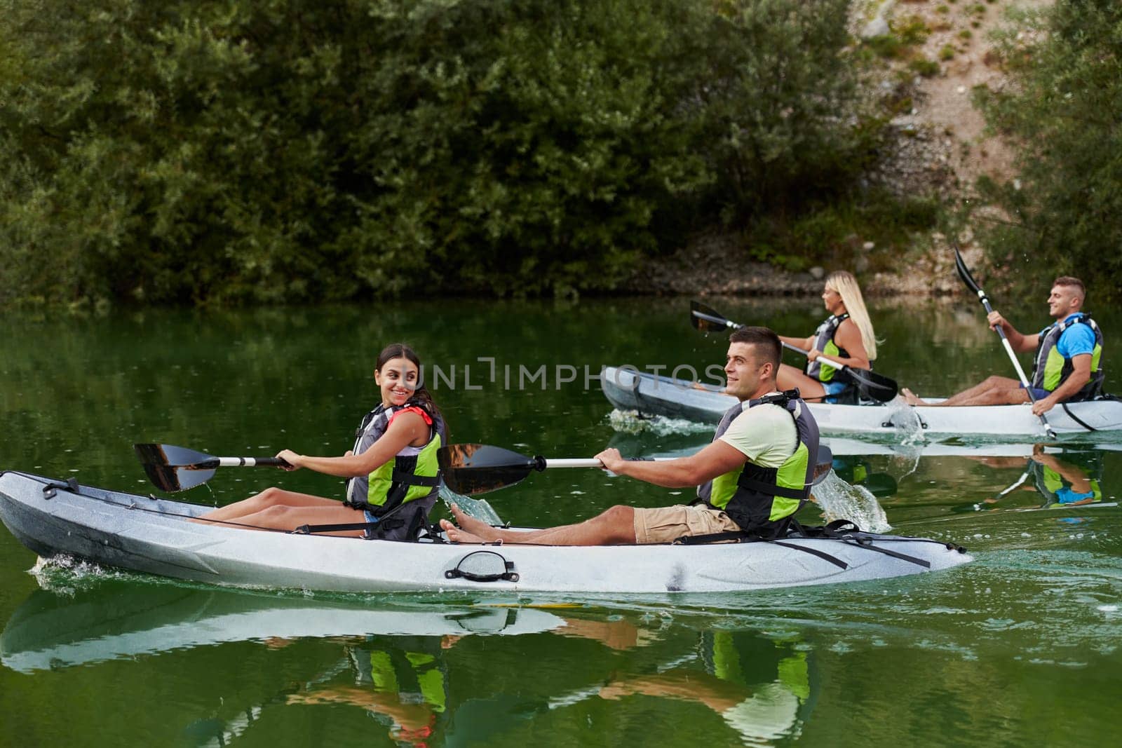 A group of friends enjoying having fun and kayaking while exploring the calm river, surrounding forest and large natural river canyons.