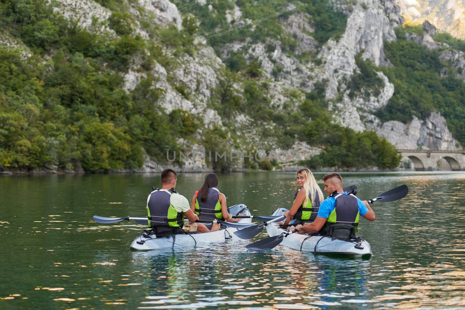 A group of friends enjoying having fun and kayaking while exploring the calm river, surrounding forest and large natural river canyons.