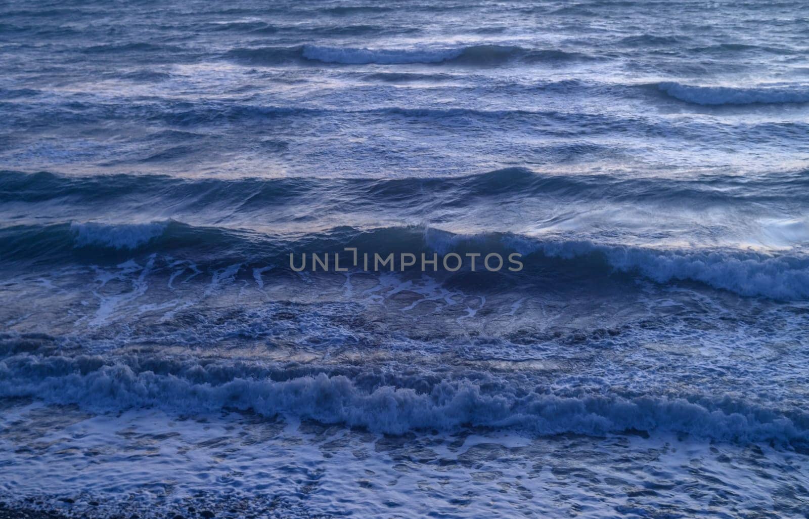 Rippled surface of blue sea water in sunset, orange and teal tones, selective focus by Mixa74