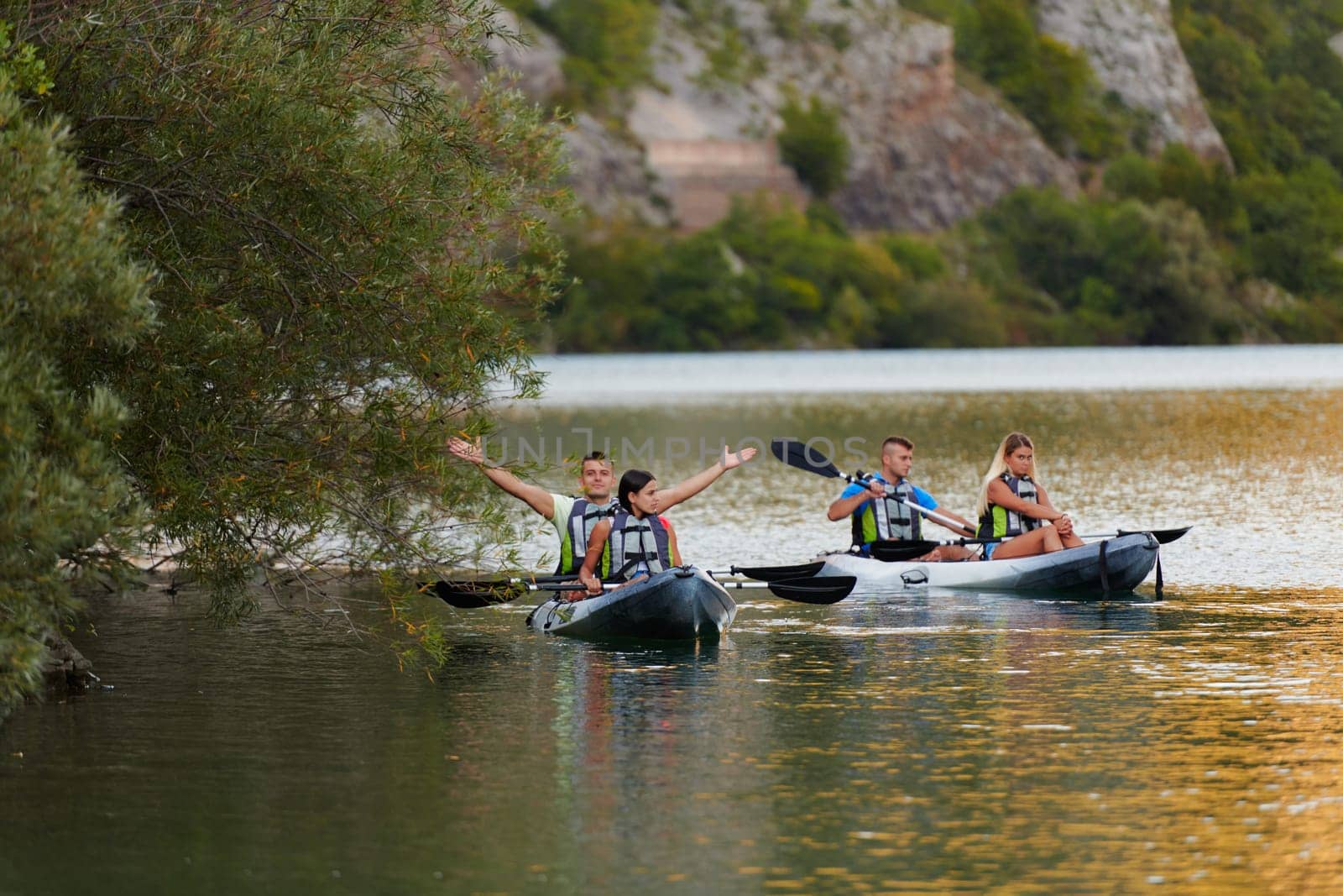 A group of friends enjoying having fun and kayaking while exploring the calm river, surrounding forest and large natural river canyons.