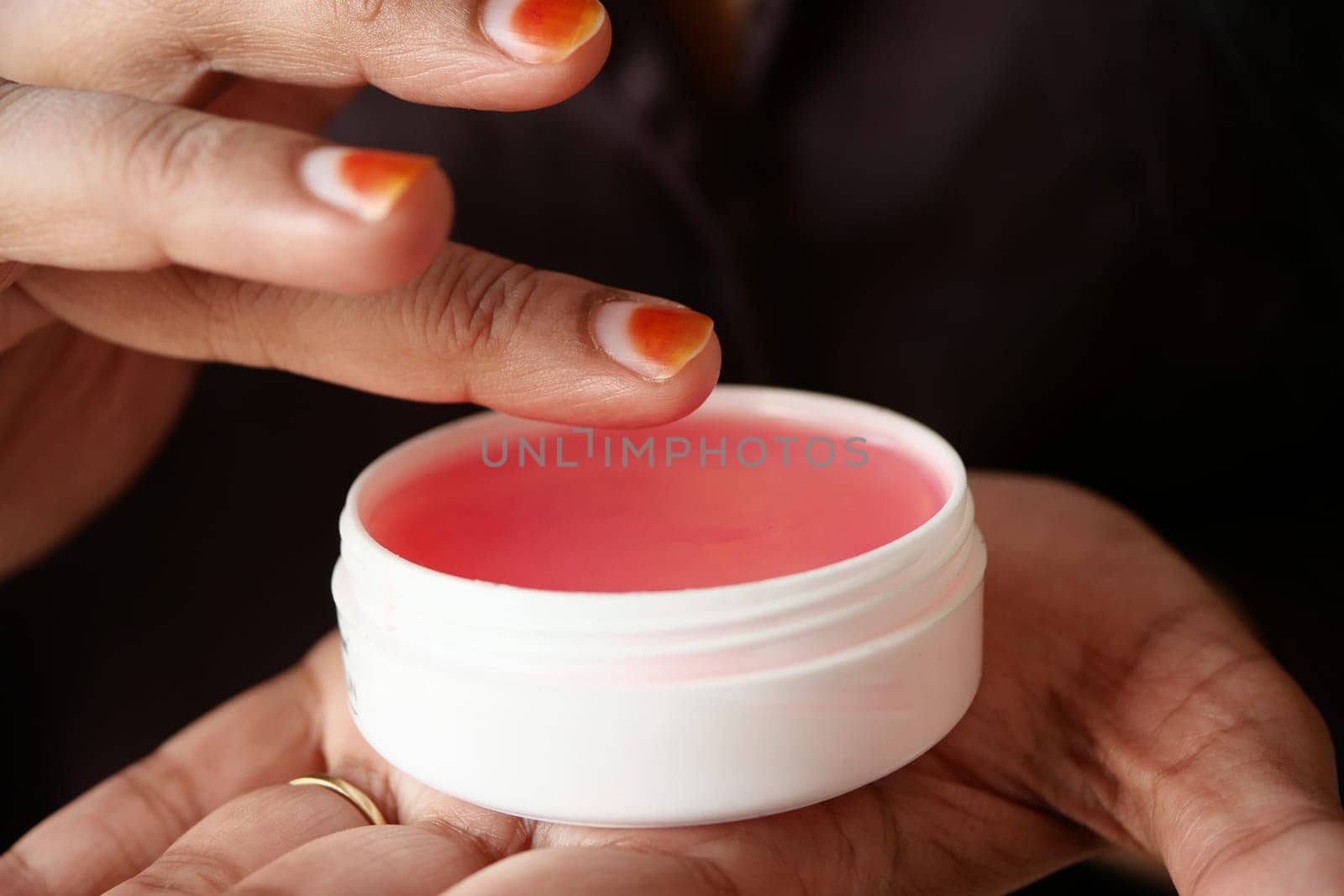 woman using petroleum jelly onto skin at home close up..