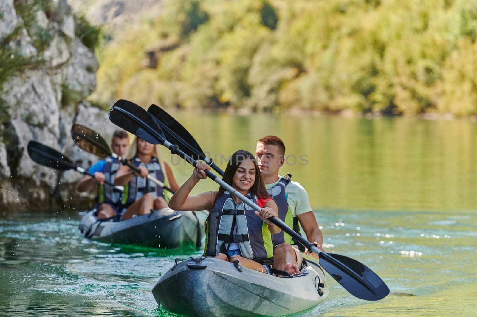 A group of friends enjoying having fun and kayaking while exploring the calm river, surrounding forest and large natural river canyons.