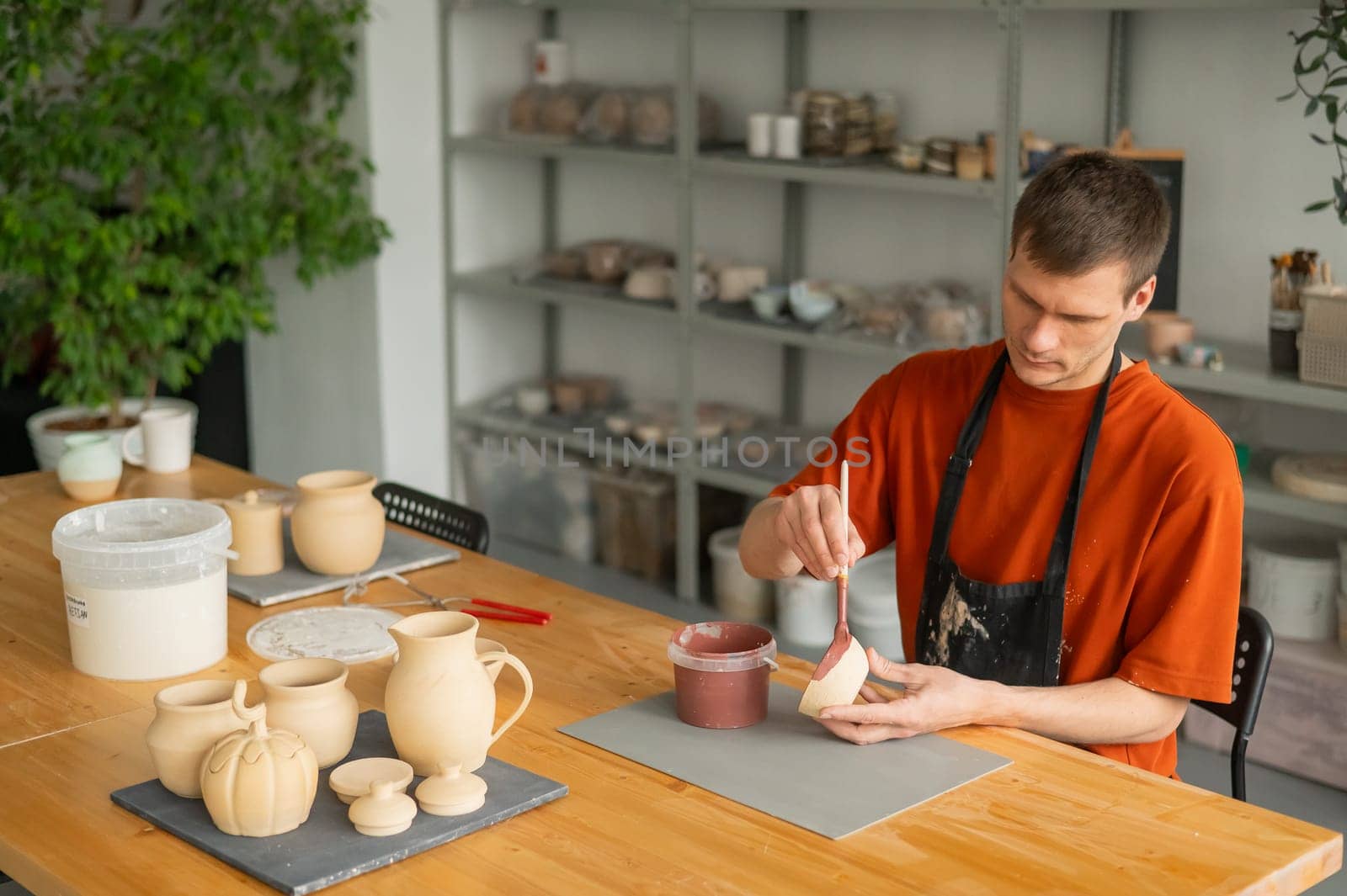 Potter paints ceramic dishes with a brush