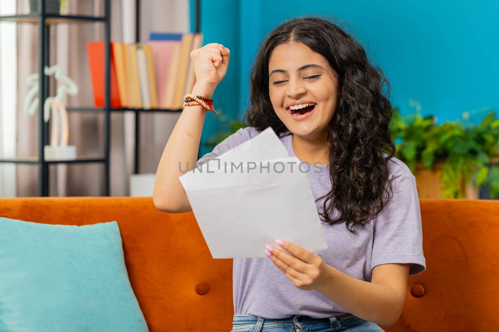 Happy Indian woman open envelope letter, reading it. Career growth advance promotion, bank loan approve, successful admission to university monetary award invitation great news, lottery game win