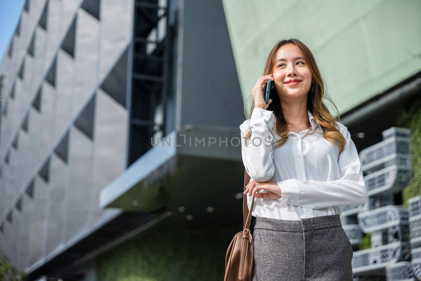 Happy businesswoman working talking on smartphone outdoor in city with client by Sorapop