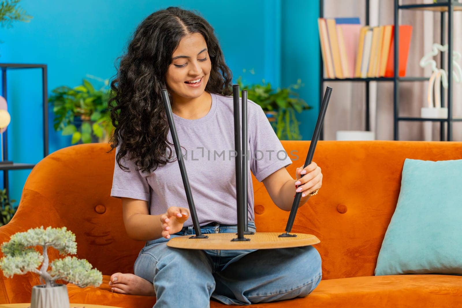 Happy Indian woman finishing assembling furniture at home. Successful table desk collect, repair fixing. Arabian Hindu girl after moving into new apartment. Advertisement of furniture store. Mortgage