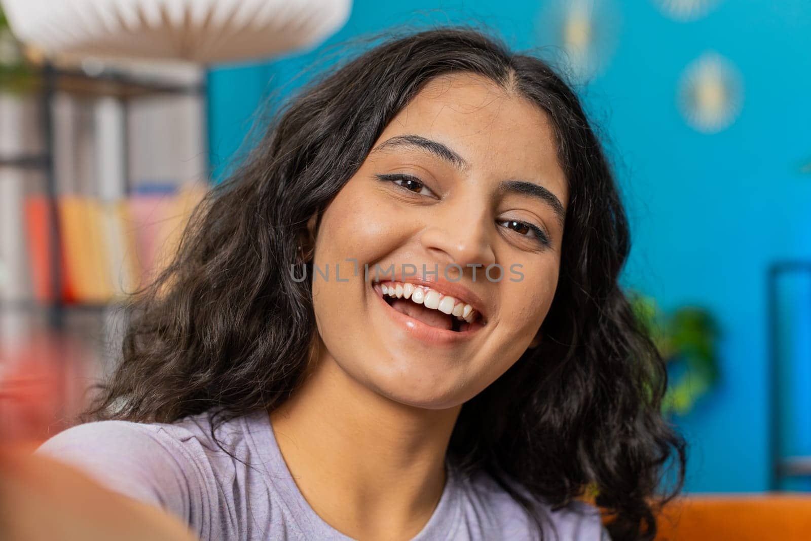 POV view of Indian young woman blogger taking selfie on smartphone communicating video call online with subscribers recording stories for social media. Happy Arabian girl holds mobile phone with hand