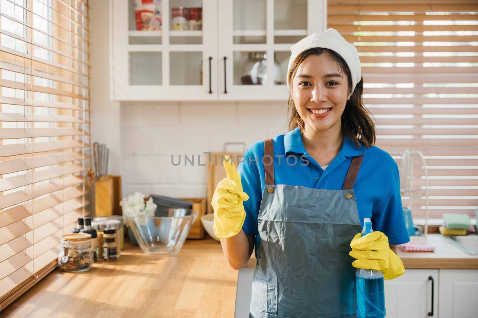 Ready for home cleaning smiling woman in uniform holds spray bottle. Emphasizing housekeeping and hygiene. Clean disinfect home care. maid with liquid.