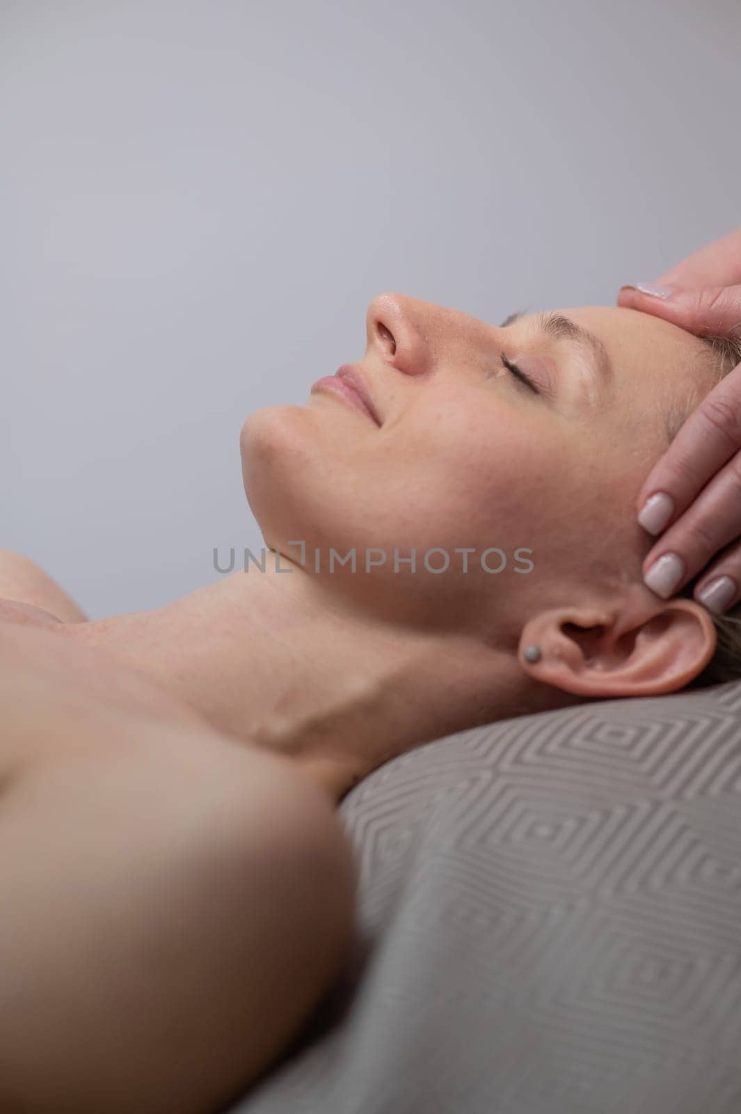 Caucasian woman undergoing a head and face massage procedure. Vertical photo. by mrwed54