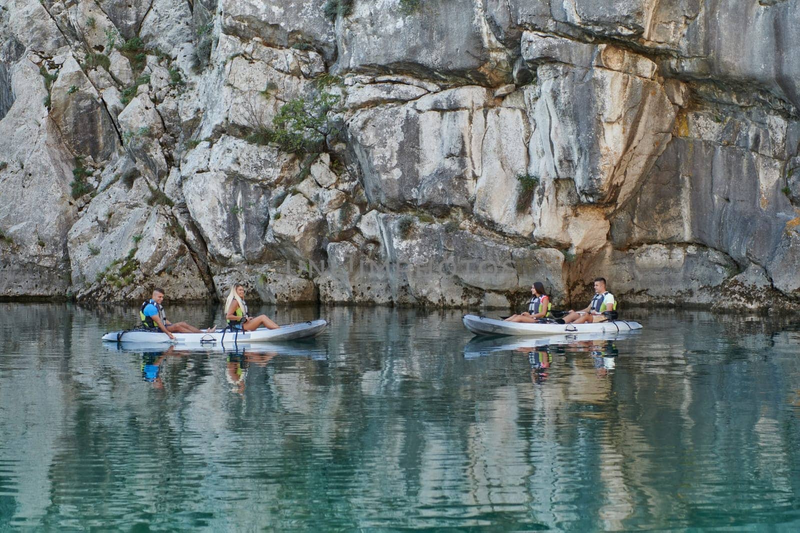 A group of friends enjoying having fun and kayaking while exploring the calm river, surrounding forest and large natural river canyons.