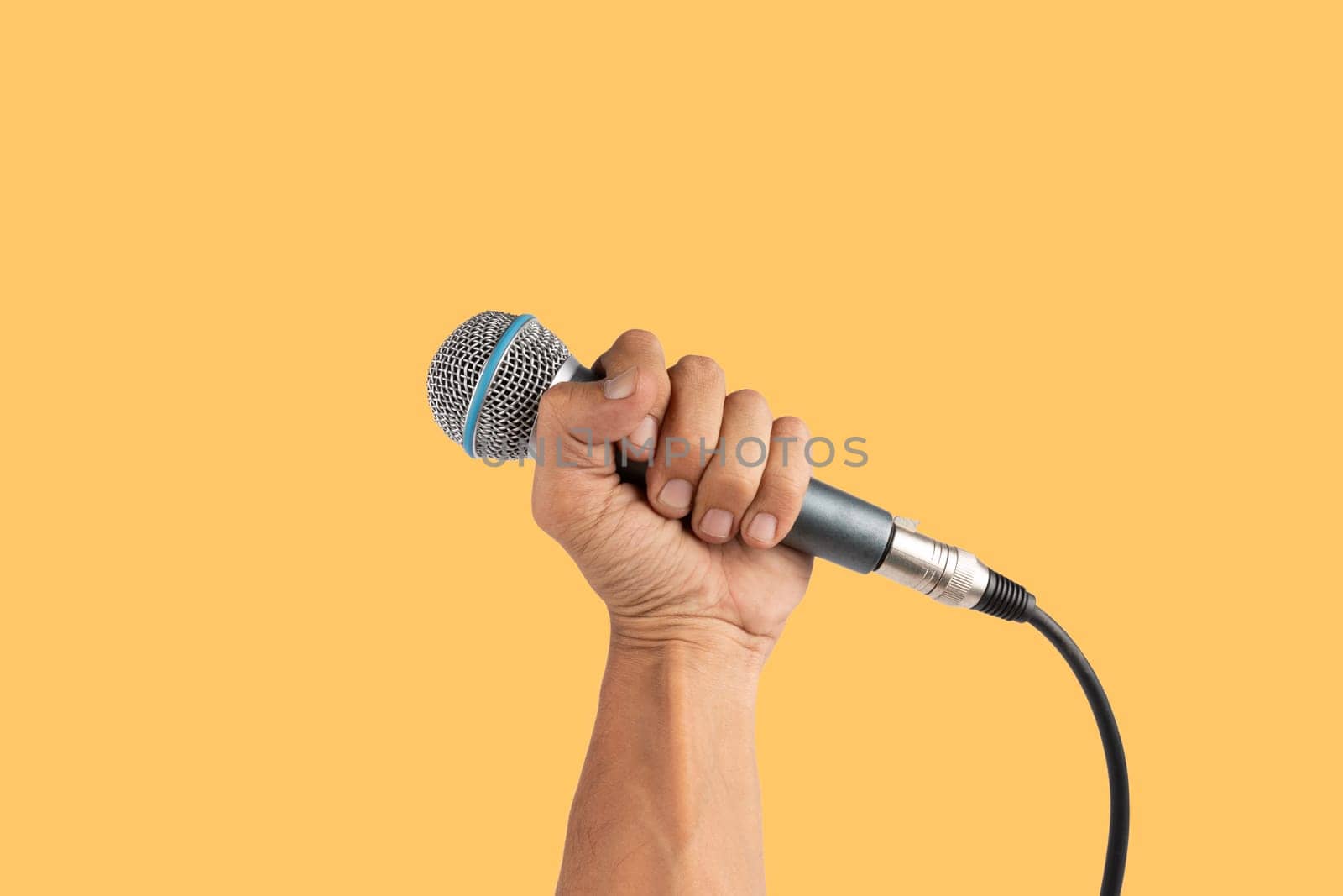 Black male hand holding a microphone isolated on yellow background. High quality photo