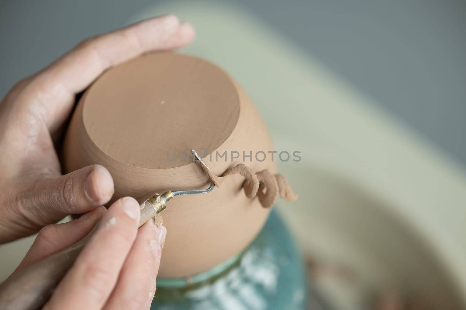 A potter works with a tool on a potter's wheel. Close-up of a man's hands