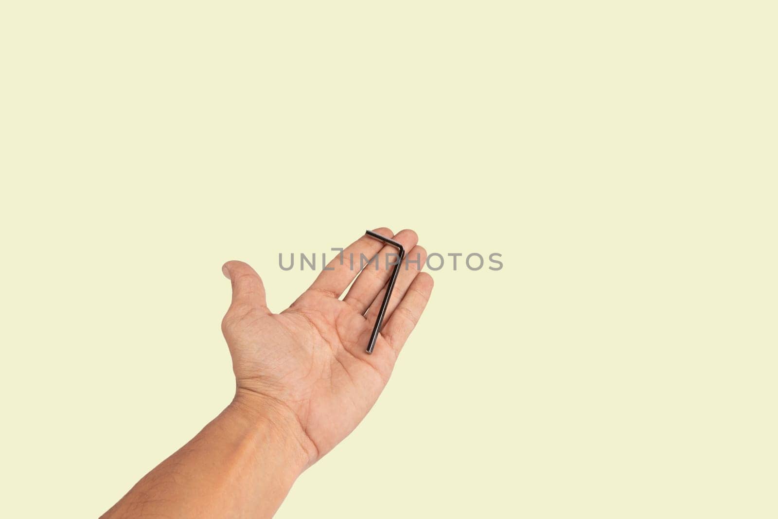 Black male hand holding an allen key isolated on light green background, cutout. High quality photo