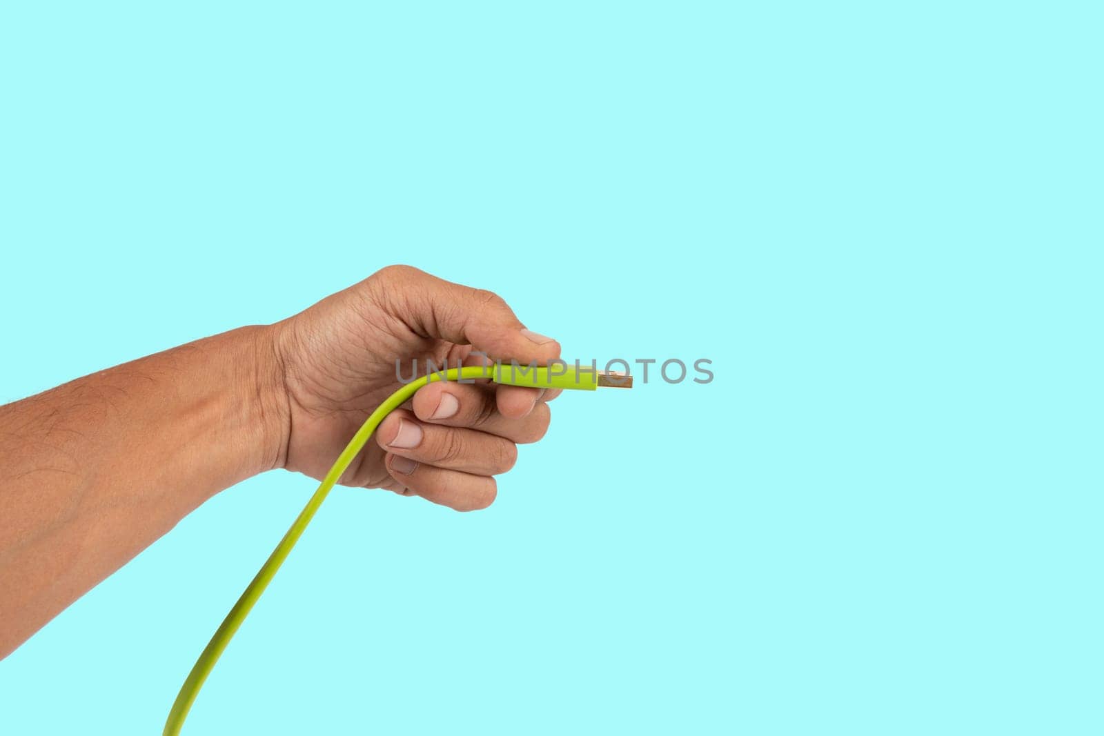 Black male hand holding a USB charger plug isolated on cyan background. High quality photo